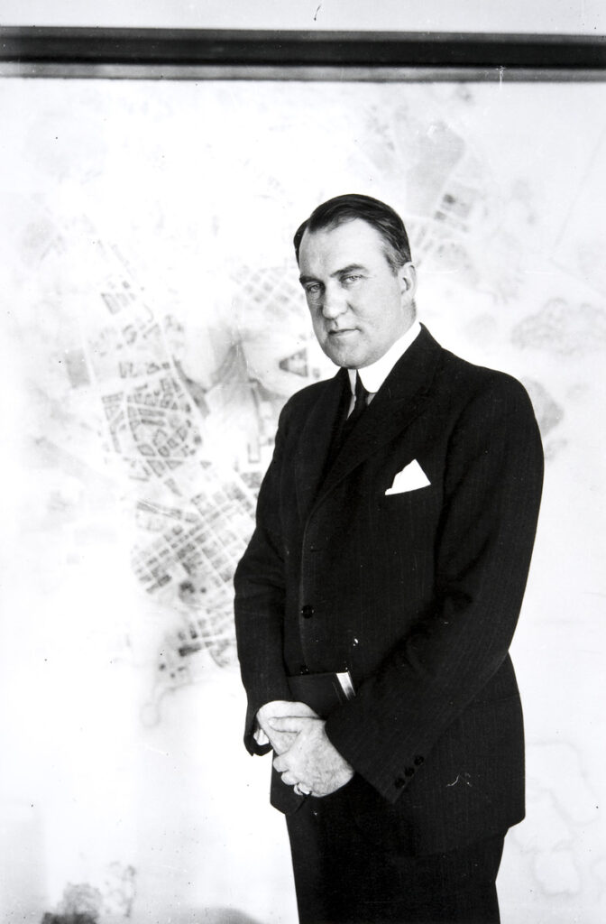 Kuvassa Erik von Frenckell, puku päällä, kartan edustalla.